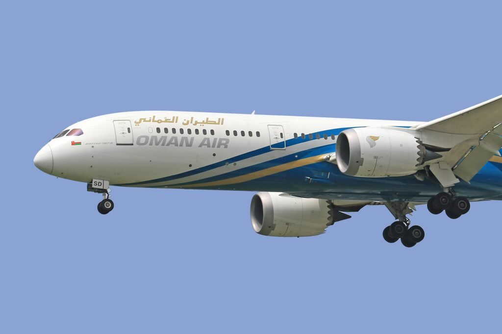 Oman Air Boeing 787 aircraft flying against a clear blue sky.